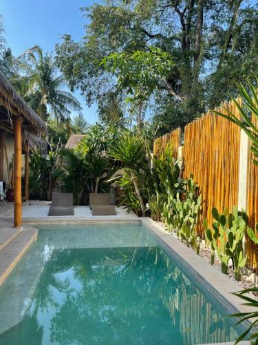 a swimming pool in front of a house with a fence at Tipsea Turtle Gili Air in Gili Air