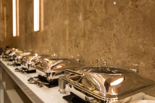 Una fila de ollas y sartenes de acero inoxidable sobre un mostrador en Hotel Shivani Udaipur, en Udaipur