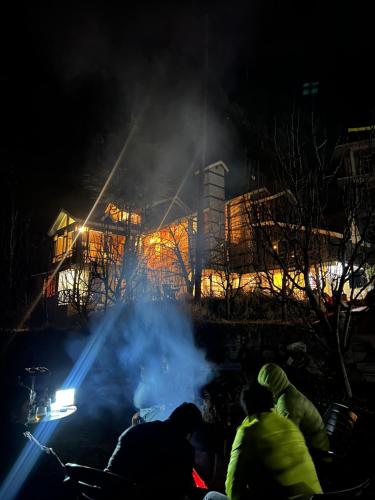 a group of people watching a fire at night at Into The Wild Manali in Vashisht