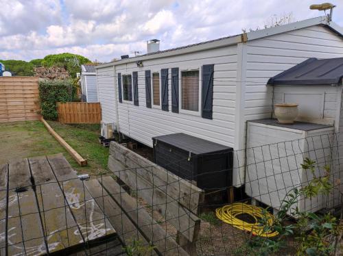 ein weißes Haus mit einem Zaun im Hof in der Unterkunft Camping La Marine in Le Grau-du-Roi