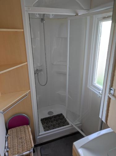 une douche avec une porte vitrée dans une salle de bain dans l'établissement Camping La Marine, au Grau-du-Roi