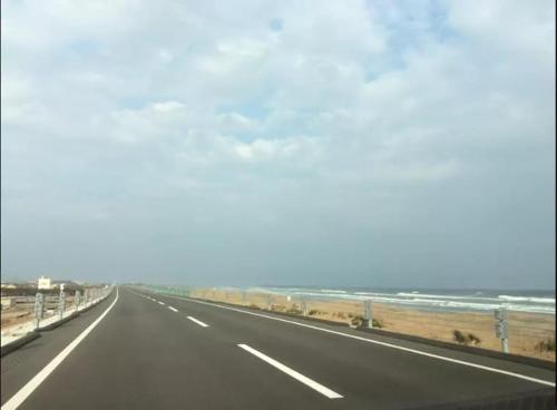 an empty highway with the ocean in the background at 10 min walk to the beach Kujukuri house for 14 ppl in Hasunuma