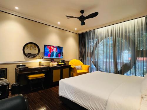 a bedroom with a bed and a desk and a tv at Hotel du Monde Art in Hanoi