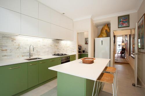 a kitchen with green cabinets and a white refrigerator at Art-Filled Designer Terrace in Chic Woollahra in Sydney