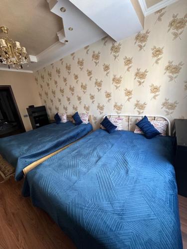 two beds in a bedroom with a blue bedspread at Altyn Horde in Almaty