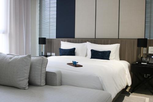 a bedroom with a large white bed and a couch at GM Estate Hotel and Executive Apartments Sukhumvit 20 in Bangkok