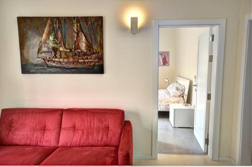 a living room with a red couch and a painting on the wall at Valletta Central Apartment in Valletta