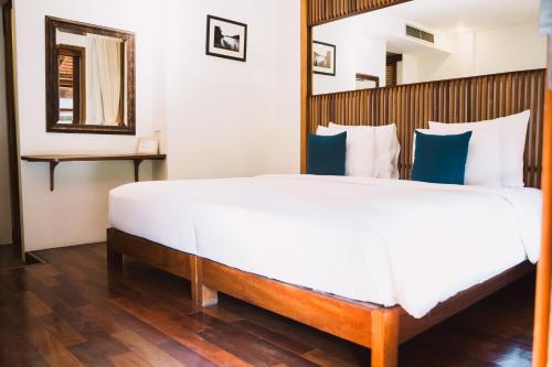 a bedroom with a large white bed and a mirror at Le Sen Boutique Hotel in Luang Prabang