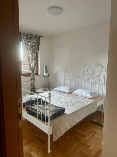 a white bed in a room with a window at M apartman, Istočno Sarajevo, Lukavica in Donje Mladice