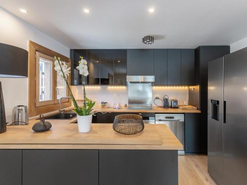 une cuisine avec des armoires noires et un comptoir en bois dans l'établissement Chalet Mitoyen à Courchevel Moriond, 4 Chambres, 8 Personnes, Ski aux Pieds, Parking, Services Inclus - FR-1-563-104, à Courchevel