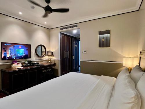 a bedroom with a white bed and a flat screen tv at Hotel du Monde Art in Hanoi
