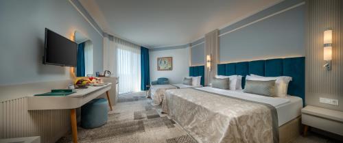 a hotel room with two beds and a desk at Pine Beach Belek in Belek