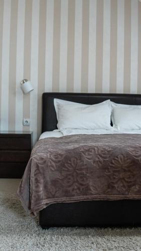 a bed with a brown blanket and white pillows at Pleasure Čair apartments in Niš