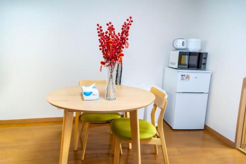 a table with a vase with red flowers in it at Sengakuji 602, 40 square meters house Direct train from the airport in Tokyo