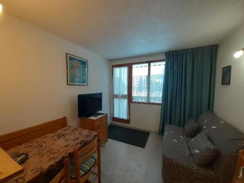a living room with a table and a couch and a television at Studio cosy 2/3 pers, proche remontées & commerces à Valfréjus - FR-1-561-88 in Valfréjus