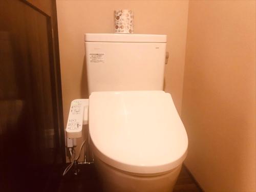a white toilet in a bathroom with a remote control at Iroriyado Hidaya in Takayama