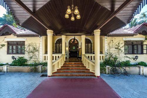 a house with a staircase leading to the front door at SaffronStays Calamondinn Bungalow, Coorg in Gonikoppal