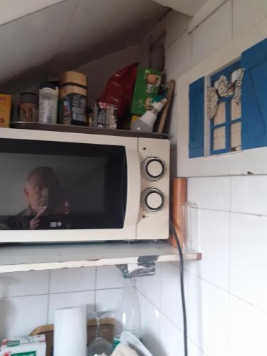 un micro-ondes posé sur une étagère dans une cuisine dans l'établissement Studette Paris 4, à Paris