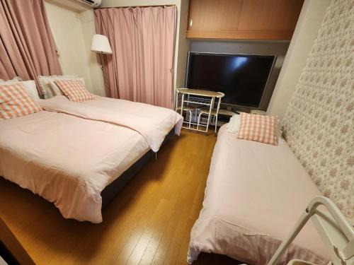 a hotel room with two beds and a television at Takaraboshi room 301 Sannomiya 10 min in Kobe