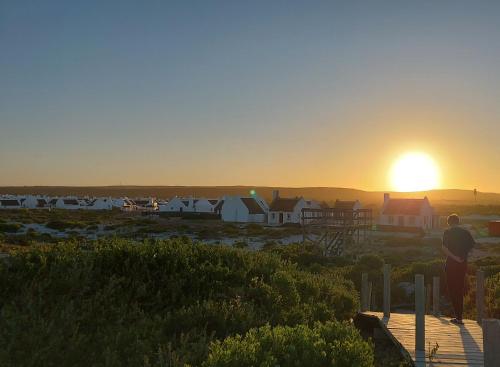 a man standing on a deck watching the sunset at 30 Beach Drive Langezandt Struisbaai in Struisbaai