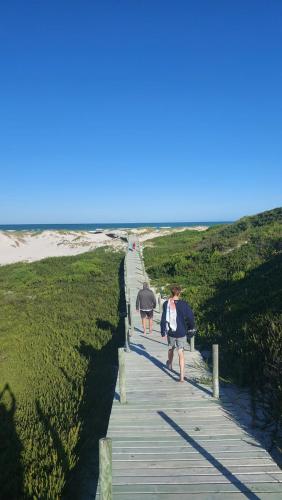 two people walking down a wooden path to the beach at 30 Beach Drive Langezandt Struisbaai in Struisbaai