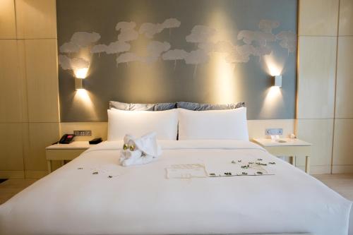 a bedroom with a white bed with a wall with clouds at Palace Resort Villas Yalong Bay Sanya in Sanya