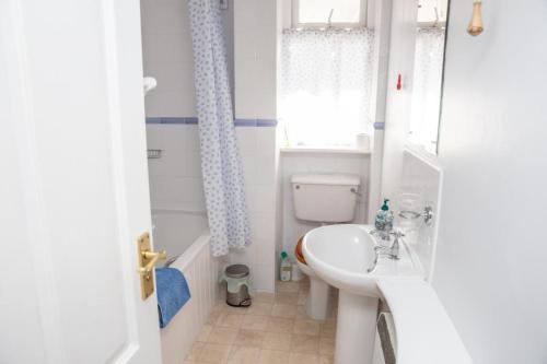 a bathroom with a sink and a toilet and a window at Sherriffs, Bantham overlooking the estuary and Burgh Island in Bigbury on Sea