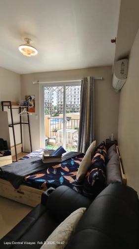 Lapu Lapu CityにあるBe Housed Studioのベッドとソファと窓のある寝室