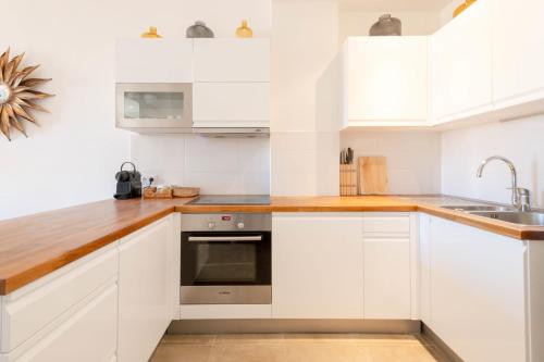 une cuisine avec des armoires blanches et un évier dans l'établissement Modern 2-Br Apartment with Balconies 3 Min from Palais des Festivals, à Cannes
