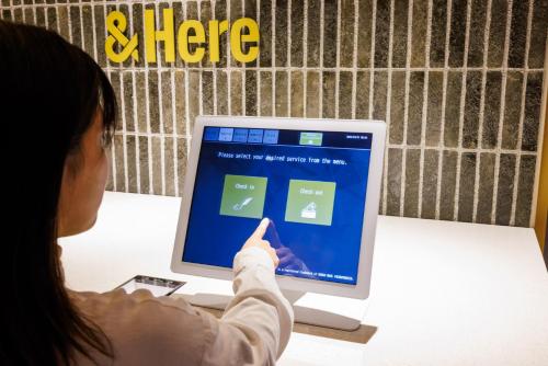 a woman pointing to a computer monitor with a person pointing at &Here TOKYO UENO in Tokyo