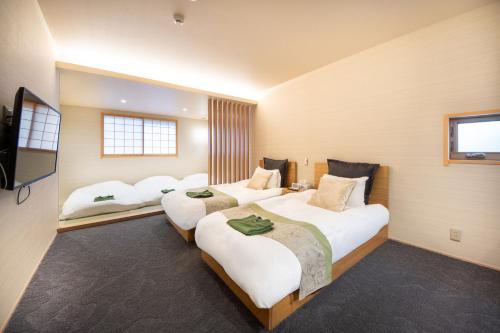 a hotel room with three beds and a television at Hotel Naranohamori in Nara