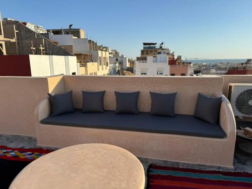 a couch sitting on top of a balcony with pillows at Playa Surf House in Tamraght Ouzdar