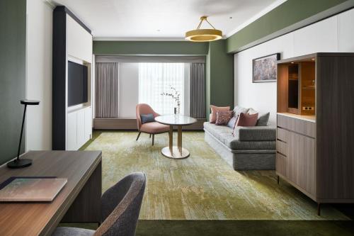 a living room with a couch and a table at RIHGA Royal Hotel Osaka, Vignette Collection by IHG in Osaka