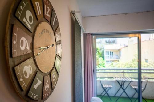 une horloge suspendue sur un mur à côté d'une fenêtre dans l'établissement Appartement climatisé tout equipe avec balcon au cœur de Marseille, à Marseille