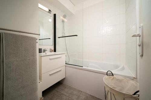 une salle de bain blanche avec une baignoire et un lavabo dans l'établissement Appartement climatisé tout equipe avec balcon au cœur de Marseille, à Marseille