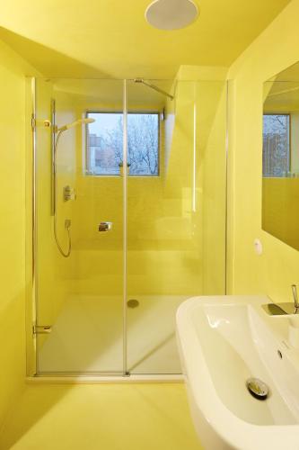 a yellow bathroom with a shower and a sink at Café FARA in Klentnice