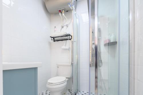 a white bathroom with a shower and a toilet at Qingdao Shanhaiji Sea View B&B Wusi Square Branch in Fushansuo