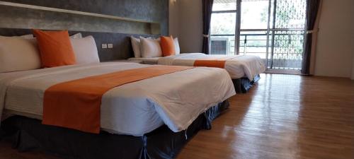 two beds in a hotel room with a window at Coconutpalm Home in Hengchun