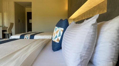 two beds with white and blue pillows in a room at Coconutpalm Home in Hengchun