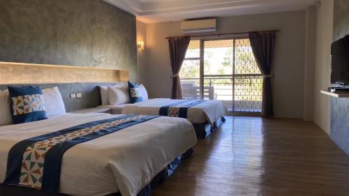 a hotel room with two beds and a window at Coconutpalm Home in Hengchun