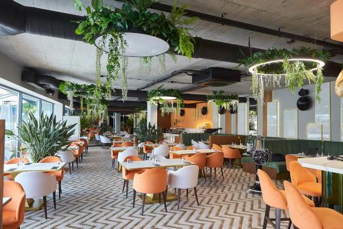 ein Restaurant mit Tischen, Stühlen und Pflanzen in der Unterkunft Laguna Resort Beskidy & Wellness in Zarzecze