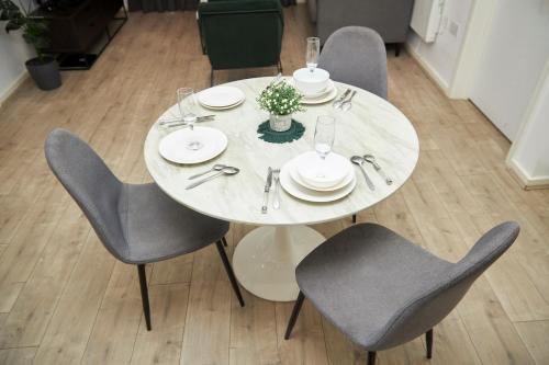 a white table with gray chairs and plates and glasses at Luxury Ensuite Apartment with shared living room and kitchen in Manchester