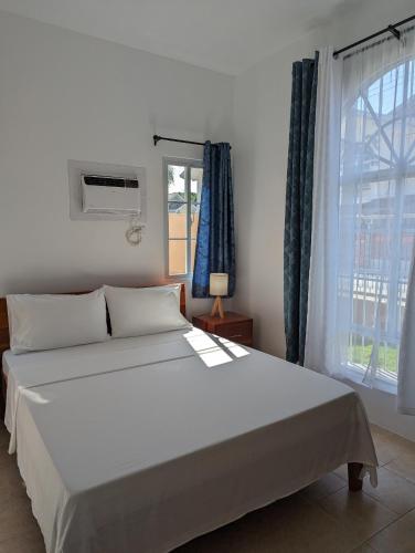 a bedroom with a large white bed and a window at Balay Hermosa in Dauis