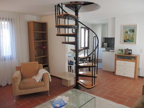 a living room with a spiral staircase and a chair at Casa Gialla by Fewotessin in Verscio