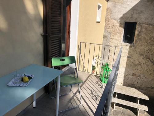 a table and a green chair on a balcony at Casa Gialla by Fewotessin in Verscio