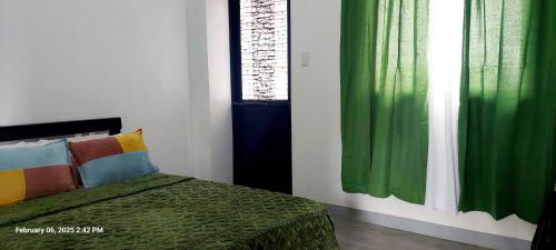 a bedroom with a bed and green curtains at Charming 2BR Apartment with Balcony and Mountain View - Logan's Transient Apartment 2 in Baguio