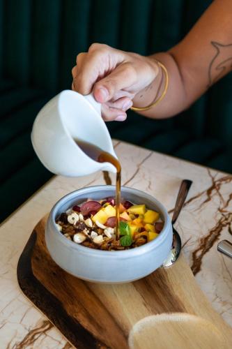 a person pouring sauce into a bowl of food at Radisson Collection Resort Galle in Galle