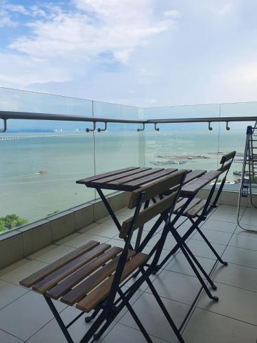 a table and a chair on a balcony with the ocean at Southbay Seaview Condo A23 #10minQueensbay in Bayan Lepas