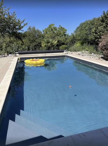 une piscine avec de l'eau bleue et des arbres en arrière-plan dans l'établissement Maison pour 6 avec piscine et grand jardin, à Plazac