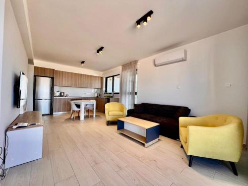 a living room with a couch and chairs and a kitchen at Mackenzie Seaside Apartment in Larnaka